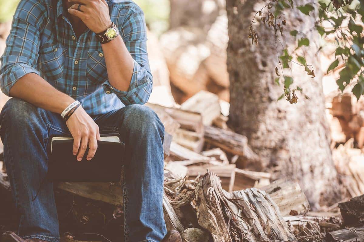 Man sitting in the nature and holding a notebook in his hand